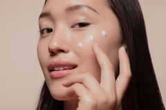 Korean woman applying skin care on her face