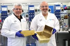 Image Two men wearing lab coats holding boxes.