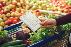 person's hand with a list of grocery items