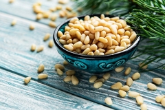pine nuts in a black bowl with green leaves on the side