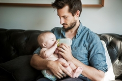 Image A man holding a baby drinking from plastic bottle