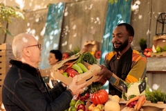 Image Senior man buying box with produce at farmers' market
