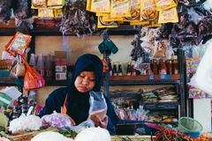 A woman at a market with items in plastic bags