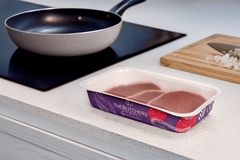 A pan next to a tray of meat