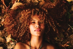 woman with curly hair laying down in nature