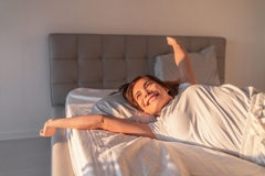 A woman awakening smiling and well rested in the rising sun.