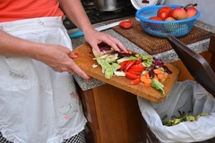 Image female hand disposing of organic waste in a clean bin with kitchen in the background