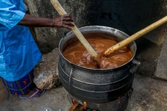 A woman making shea butter in a pot.