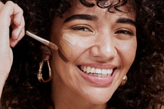 woman applying foundation on her face