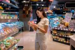 Image woman looking at QR code on product in supermarket