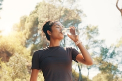 Image woman in nature drinks out of water bottle
