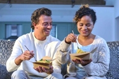 Image People on sofa eating takeaway food.