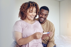 Image Happy couple with women holding pregnancy test results