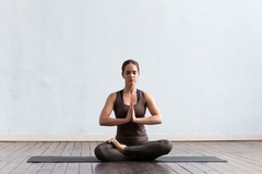 woman on yoga mat folds her hands in namste pose