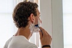 Image A man shaving his cheek.