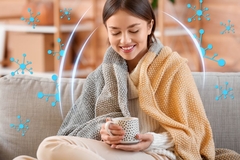young woman drinking hot tea on couch with blanket. Concept of strong immunity