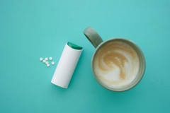 Image Artificial sweeteners and a cup of coffee on color background