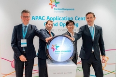 Image four men in suits touching a round symbol on stage
