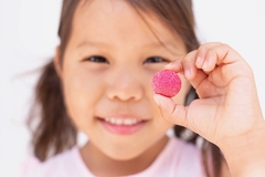 Image Young Asian girl taking a multivitamin gummy