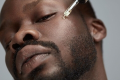 Image man applying serum to his face with a dropper
