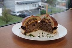 Image hybrid minced beef burger on a white plate by the window