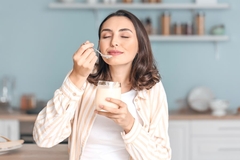 Image woman enjoys eating yogurt