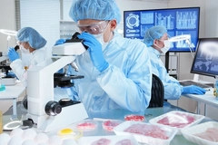 Image male scientist in lab looking through a microscope with meat samples on the table