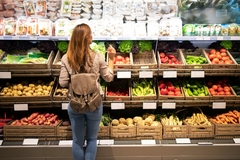 Image Woman standing in front of fresh fruit and vegetables shelves in the supermarket.