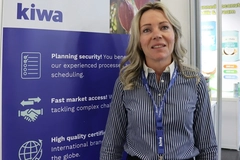 Image woman in a grey formal shirt standing at a trade show booth