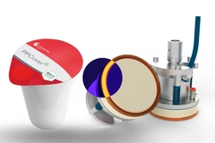Image A cup with a lid next to a circular section of a machine