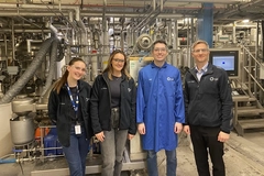 two men and two women inside food factory with fermenters in the background