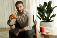 Image David Beckham sitting in a chair and preparing to drink an IM8 supplement.