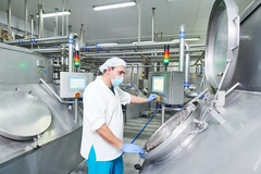 Image dairy worker with mask working on fermentation tank