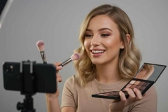 Image young woman doing makeup video for social media