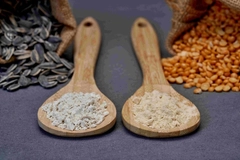 Image pea and sunflower protein in wooden spoons with sunflower seeds and peas in the background