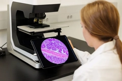 Image A woman looking at something in a microscope.