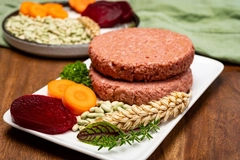 Image plant based meat patty on white plate next to beetroot and carrot slices