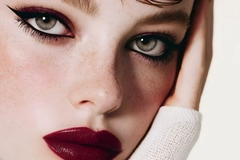 woman with red lipstick and eye makeup resting head on hands