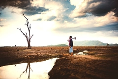 Image farmer standing on dry earth with tool next to drying river