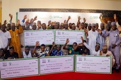A group of people holding up large check