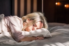 Image A woman lying in bed looking sad.