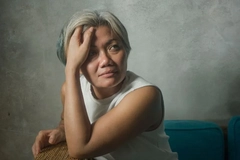 Image woman sitting on the couch with hand over forehead
