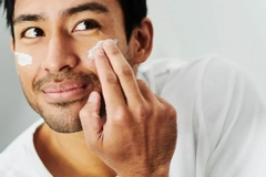 Image A man putting skin cream on his cheek.