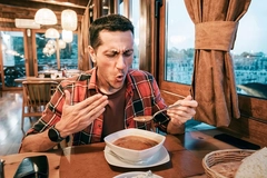 Image man in red shirt reacting to spicy bowl of soup