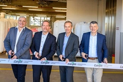 Image four men in suits cutting white ribbon inside factory