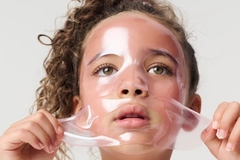 Image A little girl taking off a sheet mask from her face.