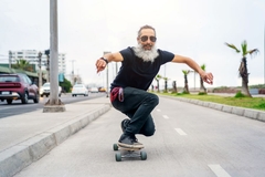 Image An older man skates down the street on a long board.