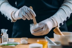 Image Woman making organic cosmetics with gloves on.