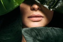 Image The bottom of a woman's face with plants in front of it.