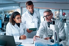 Image Men and women scientist discuss findings in a laboratory.